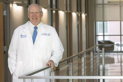 Dr. Raymond DuBois standing by a rail wearing his white doctor's coat